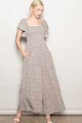 woman wearing a beige floral print maxi dress with flutter sleeves and side pockets