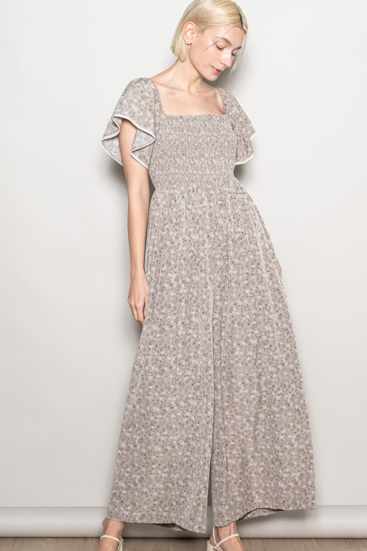 woman wearing a beige floral print maxi dress with short flutter sleeves and a square neckline