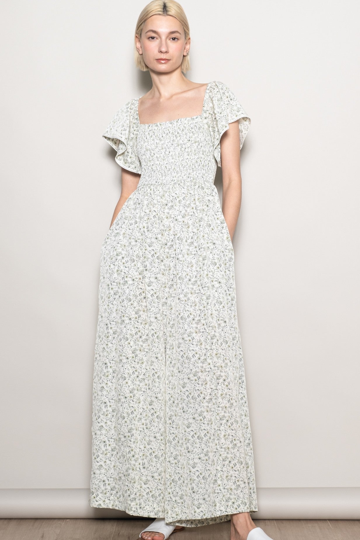 woman wearing a floral print maxi dress with short flutter sleeves and side pockets