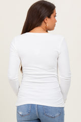 woman wearing a white long sleeve maternity top, visible baby bump, paired with blue jeans, viewed from the back