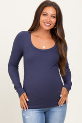 woman wearing a navy long sleeve maternity top with a scoop neck and holding her pregnant belly