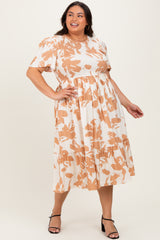 plus-size woman wearing a cream and orange floral print mid-length dress with puff sleeves and tiered skirt