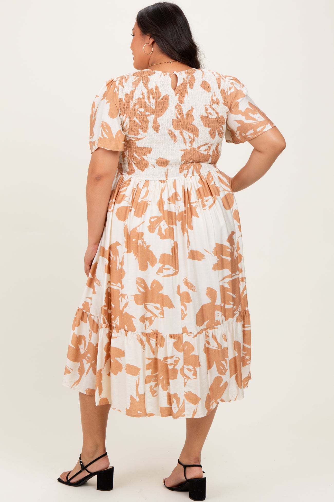 woman wearing a plus-size flowy midi dress in white with orange floral print and short puff sleeves, shown from the back