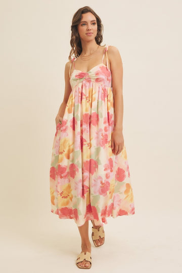 woman wearing a pink and floral print maxi dress with adjustable straps and pockets
