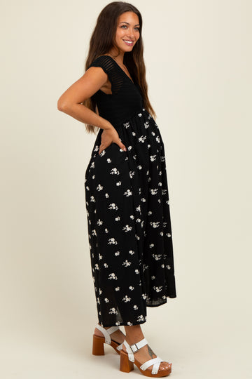 woman wearing a black floral maternity dress with a deep V-neck and pockets, showing off her baby bump