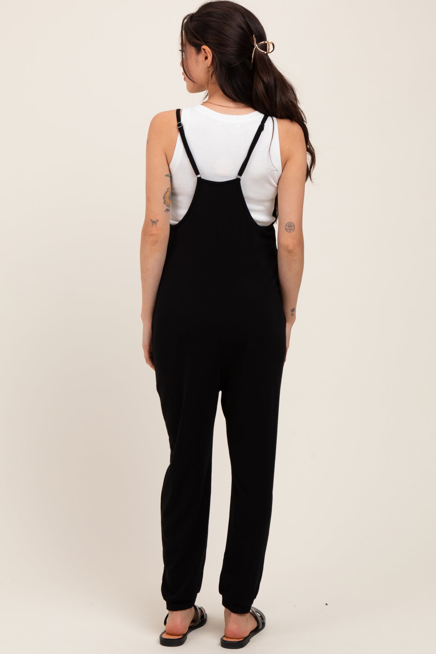 woman wearing a black maternity jumpsuit with spaghetti straps, viewed from the back