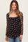 woman wearing a black floral maternity top with sheer long sleeves and a visible baby bump