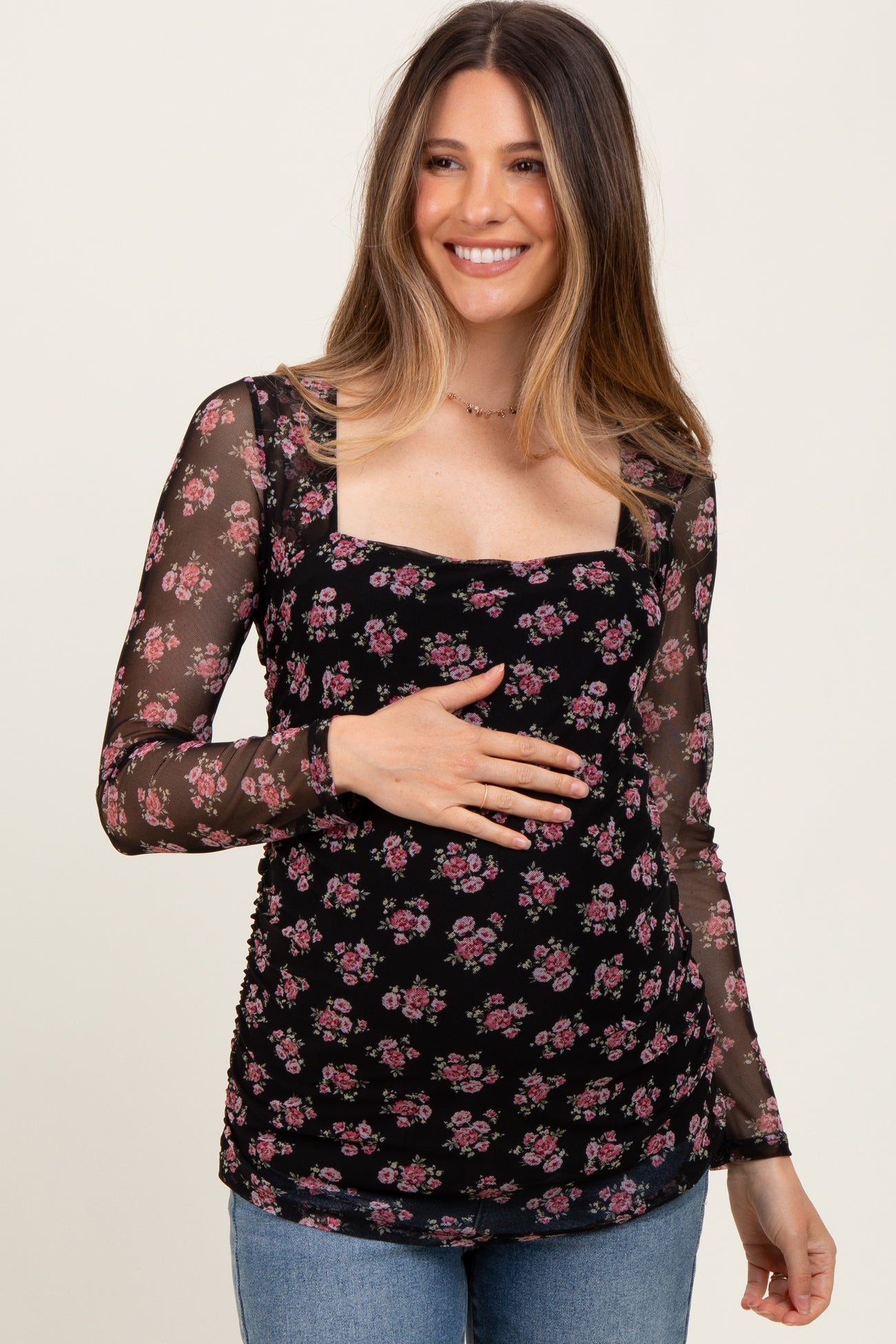 woman wearing a black floral maternity top with long sheer sleeves and a visible baby bump