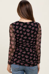 woman wearing a black floral maternity top with sheer long sleeves, viewed from the back