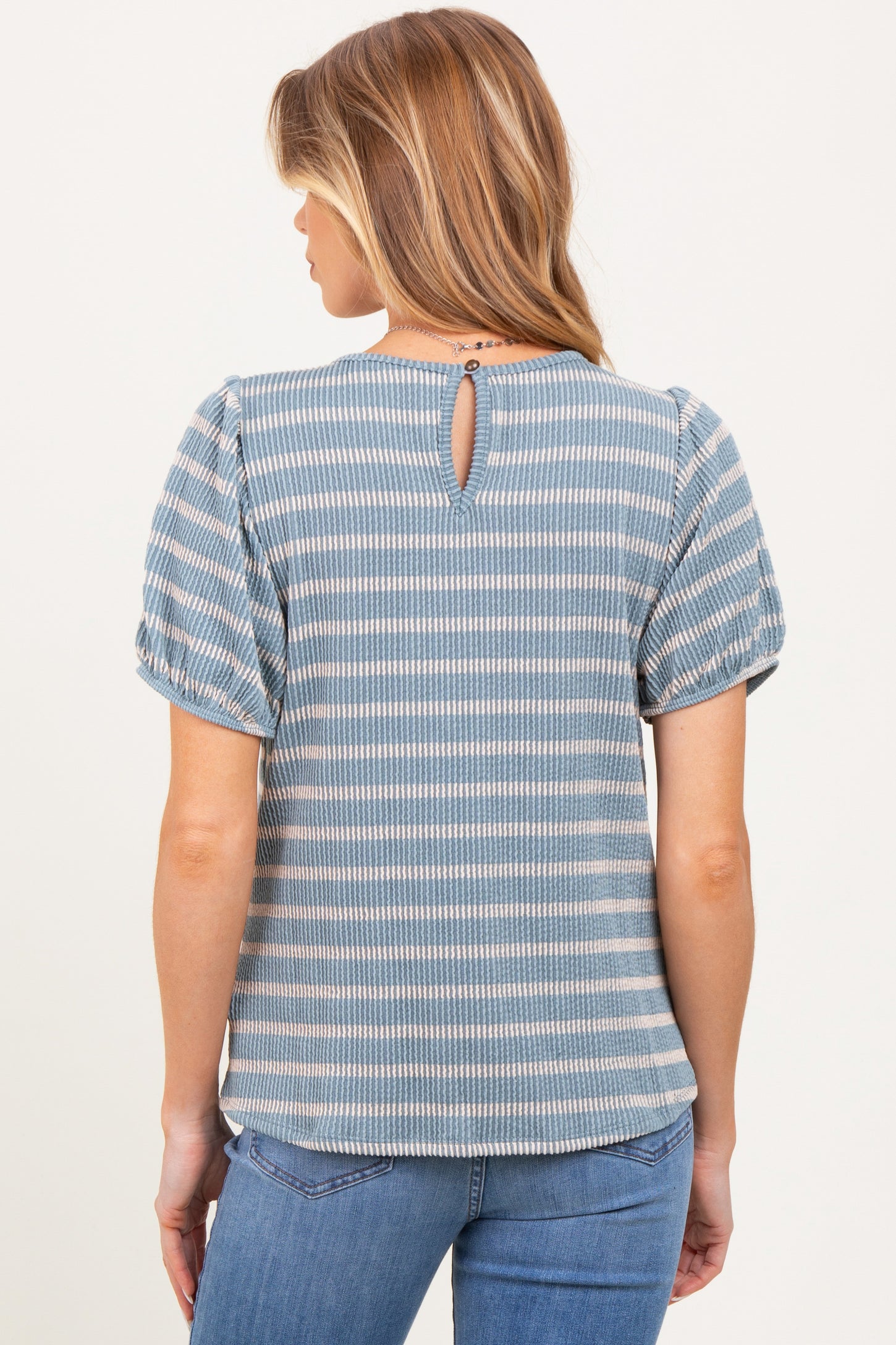 woman wearing a blue striped maternity top with puff sleeves and a keyhole back detail