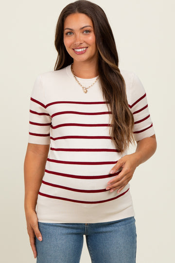 woman wearing a cream and red striped maternity top, showing her baby bump and styled with jeans