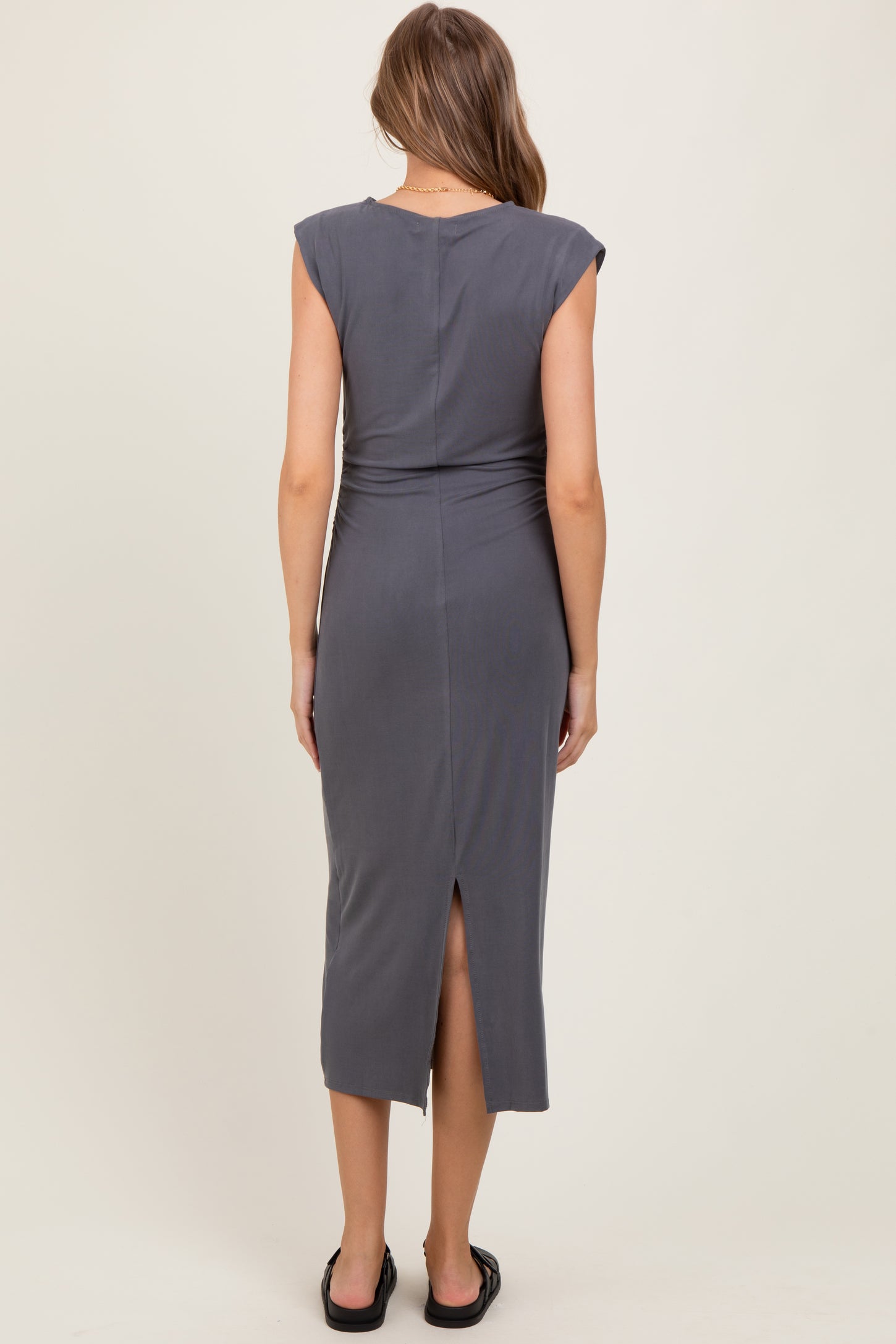 woman wearing a dark gray fitted midi dress with cap sleeves and a back slit