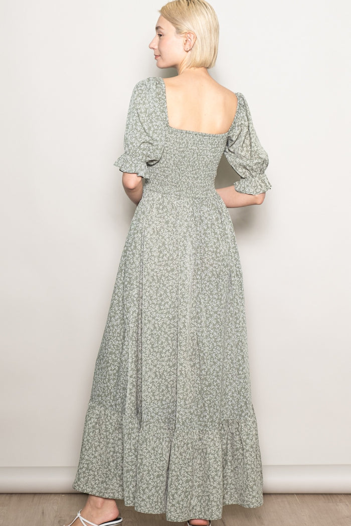 woman wearing a green floral maxi dress with puff sleeves and a square neckline, shown from the back