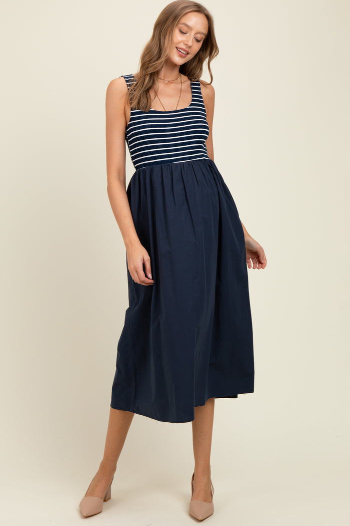 woman wearing a navy blue and white striped maternity dress with a flowing skirt and adjustable straps