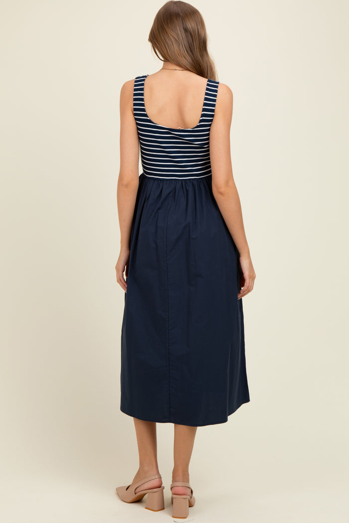 woman wearing a navy and white striped maternity dress with a fitted bodice and flowy skirt, showing a baby bump from behind
