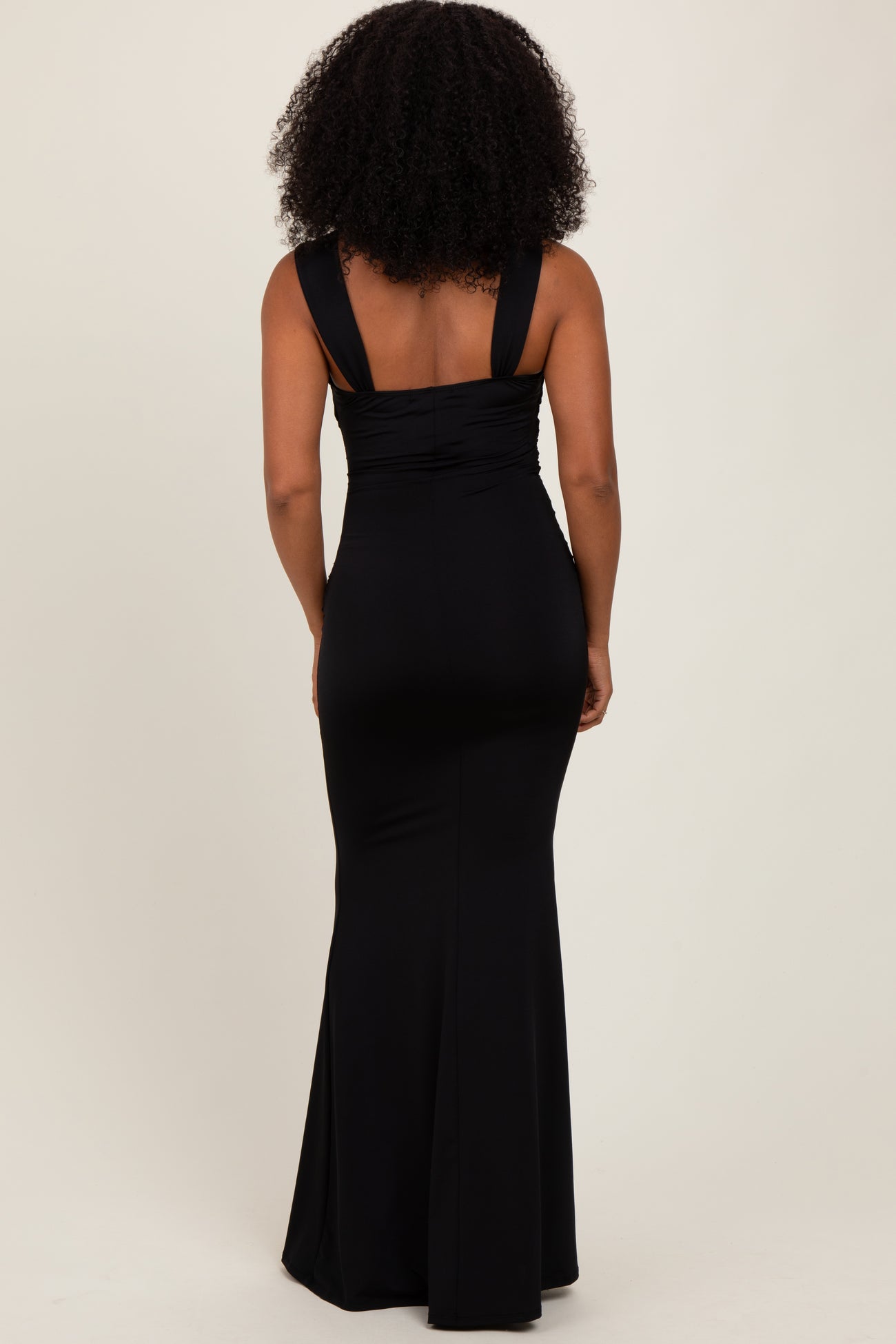 woman wearing a black fitted maxi dress with wide straps and a slight flare at the hem, shown from the back