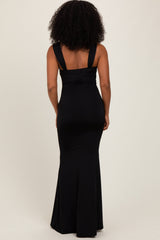 woman wearing a black fitted maxi dress with wide straps and a slight flare at the hem, shown from the back