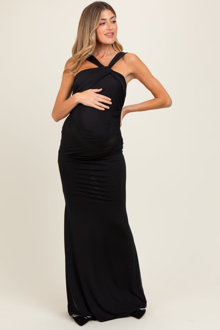 woman wearing a black maternity maxi dress with crisscross straps and showcasing her baby bump