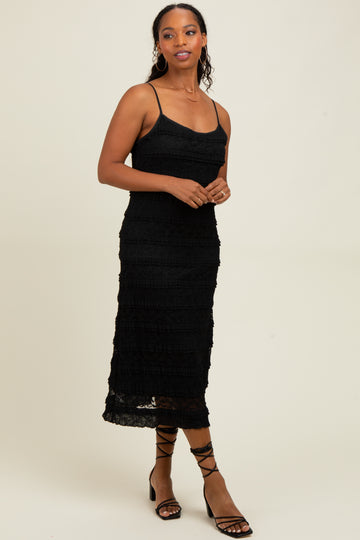 woman wearing a black spaghetti strap midi dress with a tiered ruffle design and styled with strappy black sandals