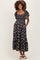 woman wearing a black floral maternity dress with short puff sleeves and pockets, showing her baby bump