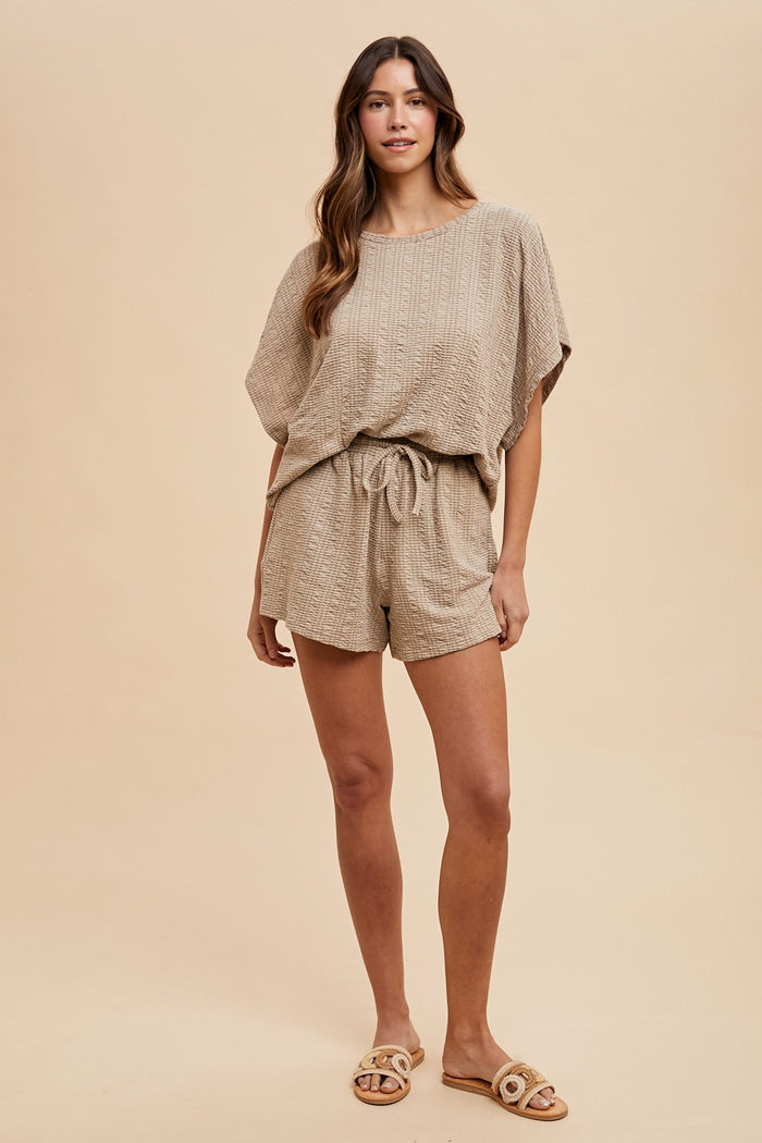 woman wearing a beige patterned knit short set with a drawstring waist and relaxed fit, styled with comfortable sandals