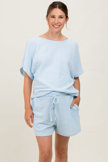 woman wearing a light blue maternity two-piece set with a loose-fitting top and shorts, featuring a textured pattern