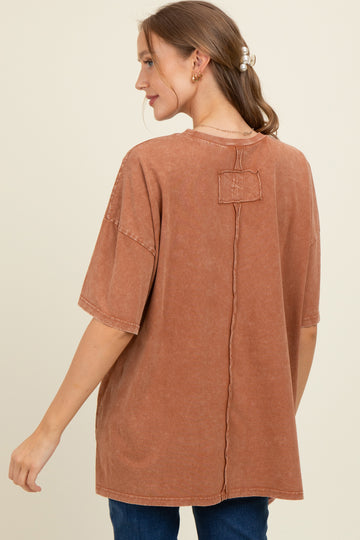 woman wearing a rust-colored oversized maternity tee with a relaxed fit and back seam detail