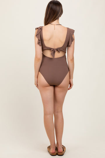 woman wearing a brown maternity swimsuit with ruffle details and a tie-back design