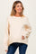 woman wearing a light beige oversized maternity sweater and dark blue jeans