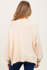 woman wearing a beige oversized maternity sweater with a loose fit, showing the back view