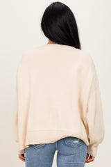 woman wearing a cream oversized sweater with a ribbed hem and back, paired with light blue skinny jeans