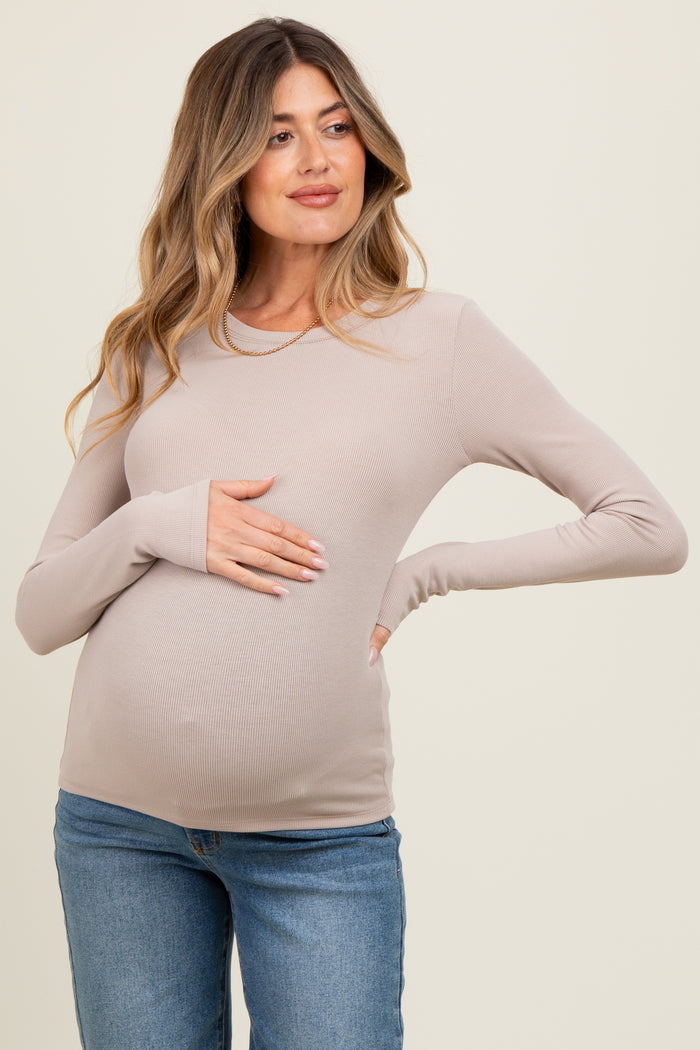 woman wearing a light beige long sleeve maternity top and holding her baby bump
