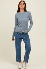 woman wearing a light blue long sleeve ribbed top and high-waisted blue jeans with white sneakers