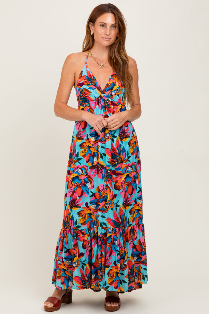 woman wearing a vibrant floral print maxi dress with a halter neckline and tiered hem