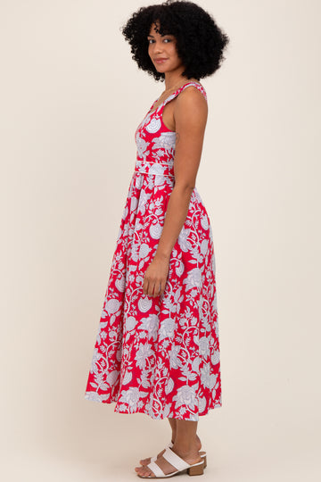 woman wearing a red floral midi dress with a fitted bodice and flared skirt, standing in profile