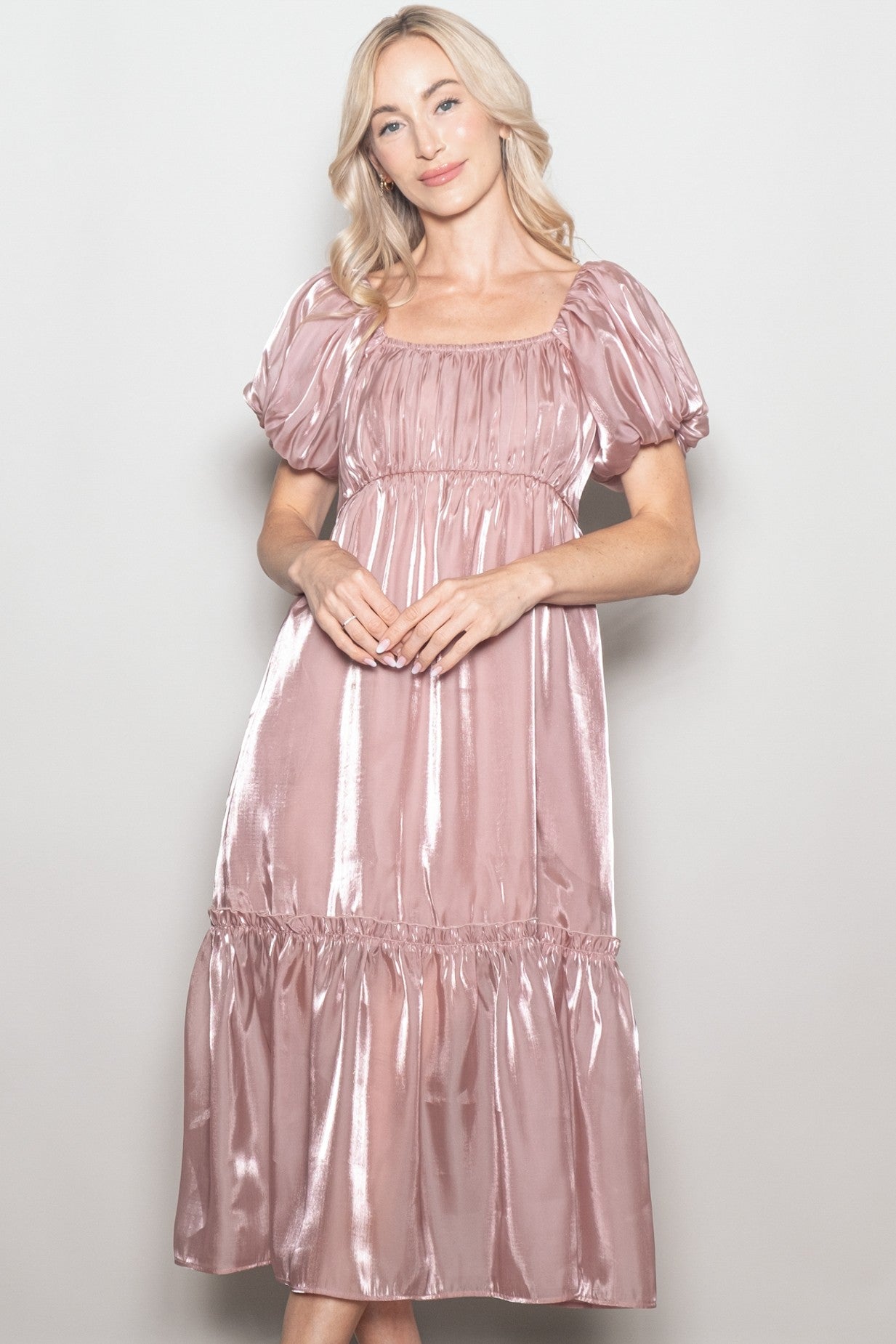 woman wearing a shiny blush pink puff sleeve midi dress with a square neckline and tiered skirt