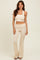 woman wearing a cream ribbed two-piece set with a square neck crop top and flared pants