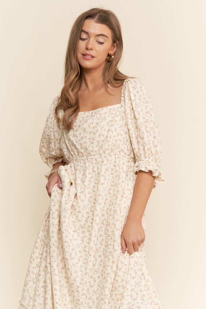 woman wearing a cream floral midi dress with puff sleeves and a square neckline