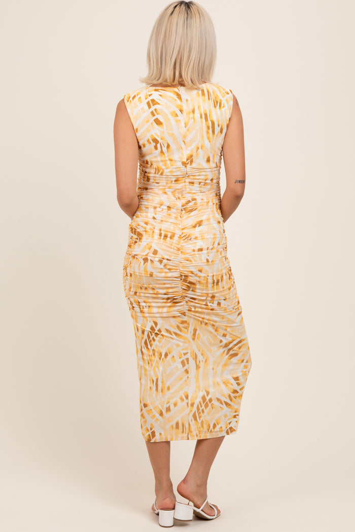 woman wearing a yellow and white tie-dye maternity dress with ruched detailing, showing her back