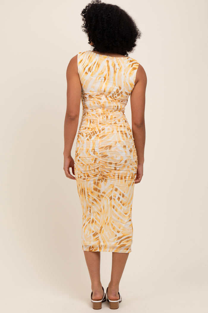woman wearing a fitted midi dress with a yellow and white abstract print, featuring ruching detail on the back