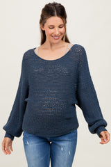 woman wearing a navy knitted maternity sweater with a relaxed fit and a visible baby bump, paired with blue jeans