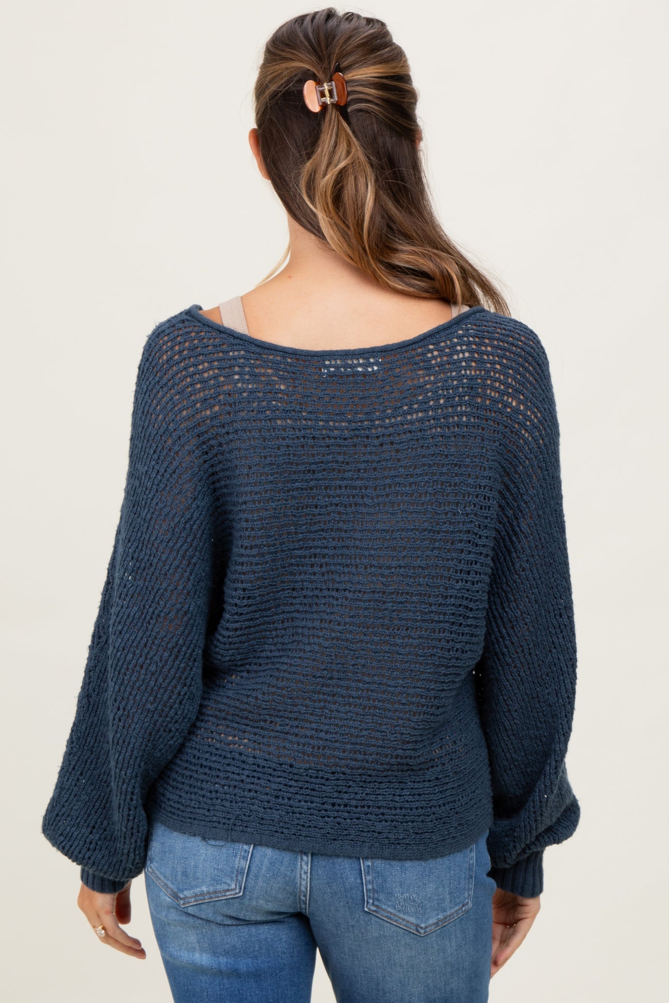 woman wearing a navy blue open-knit maternity sweater with a loose fit and bell sleeves