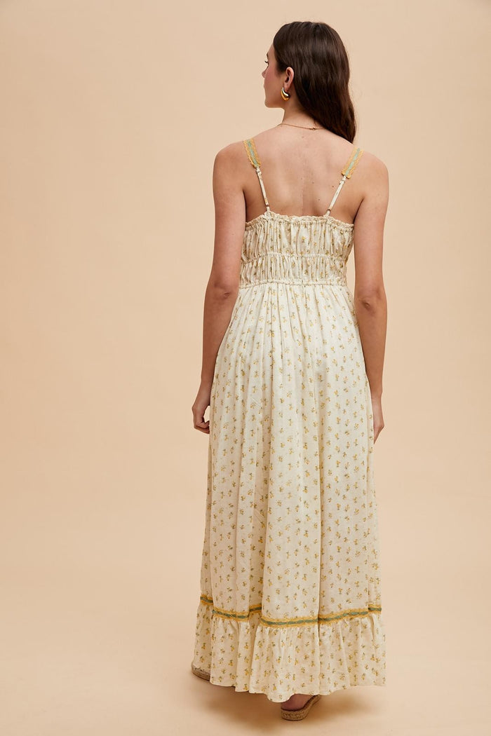 woman wearing a cream floral maxi dress with a smocked bodice and ruffled hem, viewed from the back