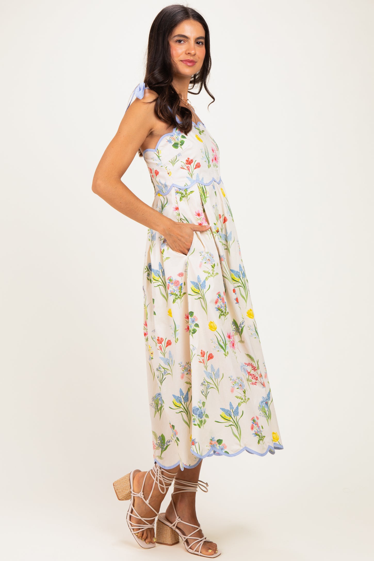 woman wearing a floral print midi dress with a halter neck and pockets, styled with strappy sandals