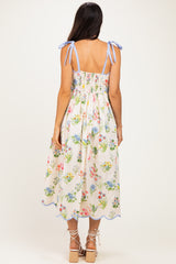woman wearing a floral print midi dress with blue shoulder ties and a smocked back detail