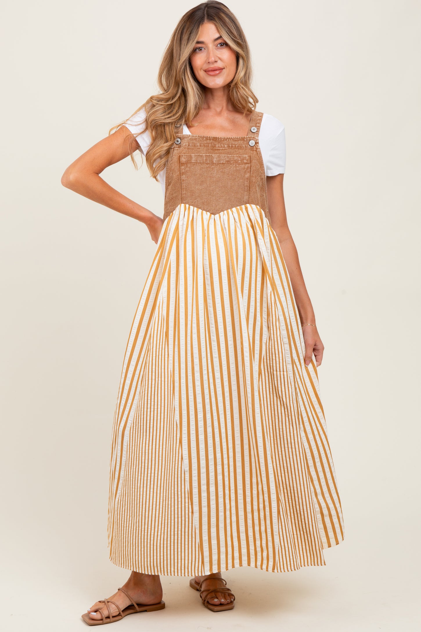 woman wearing a tan and white striped maternity maxi dress with a fitted bodice and flared skirt