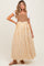 woman wearing a tan and white striped maternity maxi dress with a fitted bodice and flared skirt