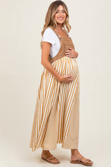 woman wearing a mustard striped maternity dress with a white t-shirt underneath, holding her baby bump