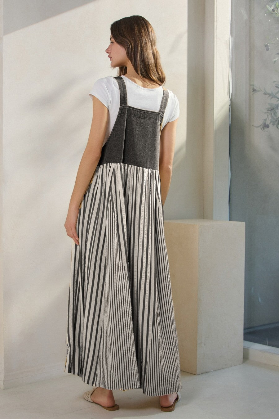 woman wearing a black and white striped maxi dress with a fitted top and flared skirt, showing the back view