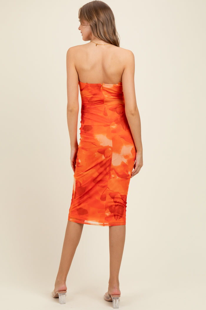 woman wearing a strapless orange floral maternity dress, showcasing a form-fitting silhouette and mid-length cut